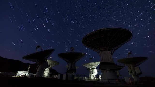 Radio telescopes beneath swirling star trails at night
