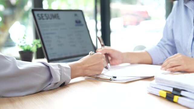 HR manager interviewing a job candidate across a desk, discussing qualifications and experience during a recruitment meeting in a modern office environment.