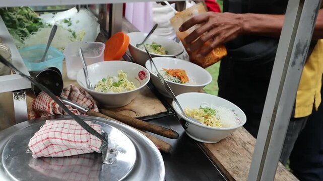 Food vendor preparing bowls of traditional meatball soup for customers.