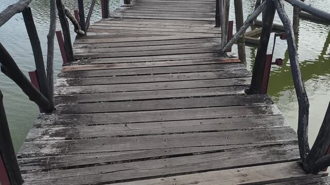 A wooden boardwalk bridge curving across a lake