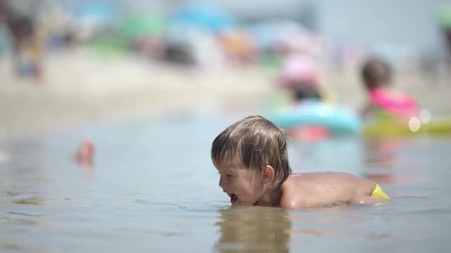 Kid collects shells and pebbles in the sea on a sandy bottom under the summer sun on a vacation