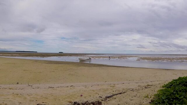 Scenic view of sandy beach and fishing boat with ocean low tide in Buka on tropical island of Bougainville, Papua New Guinea