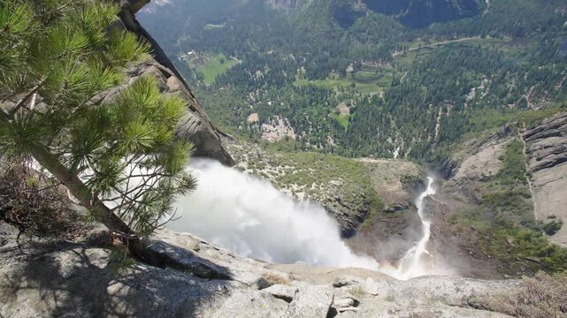 Top of Upper Yosemite Falls tilting down to reveal water crashing and valley below in Yosemite National Park, California.