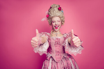 Fototapeta premium Photo of excited lady princess blinking eye making thumb up symbol wear medieval theme costume isolated pink color background