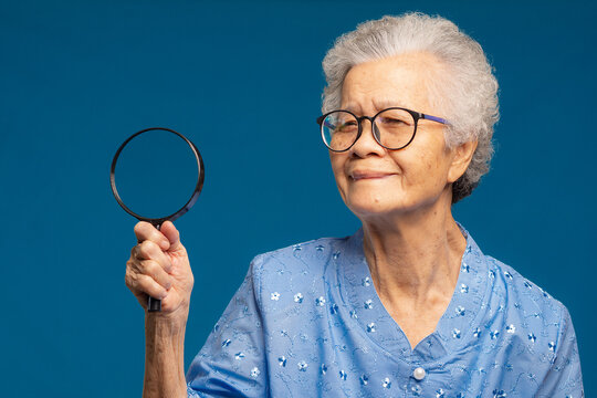 Senior Woman Holding Magnifying Glass on Teal Background