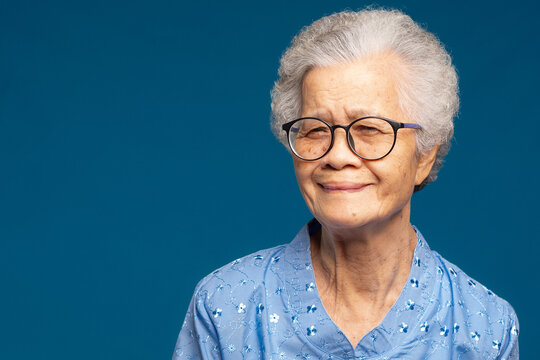 Senior Woman Smiling in Blue Shirt on Teal Background