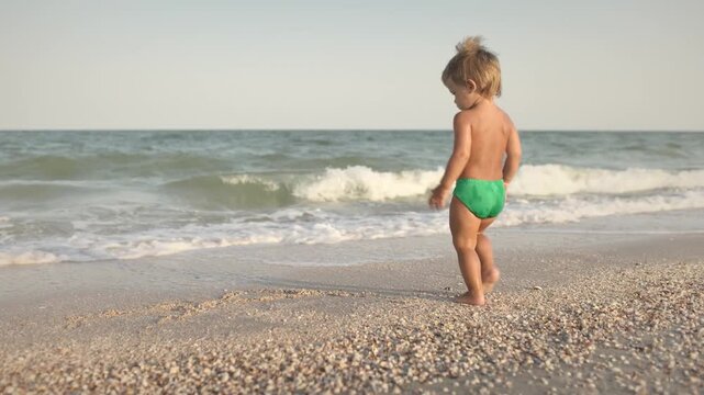 Kid collects shells and pebbles in the sea on a sandy bottom under the summer sun on a vacation