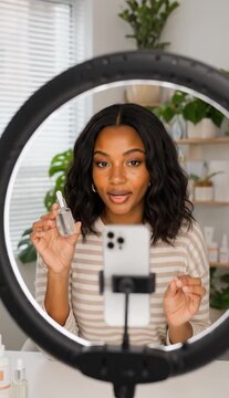 Beauty influencer presenting a facial serum while recording a skincare tutorial on a smartphone with a ring light in a bright home studio