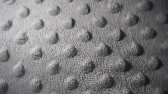 Extreme close-up of soft dotted minky fabric texture with moving light and shadow transitions