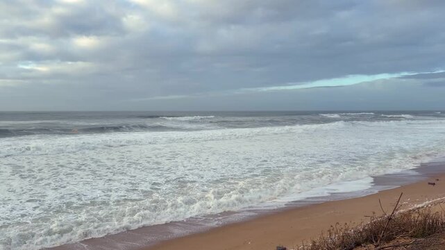 LabeStatic 4K video of the Atlantic coast at Labenne Oc&eacute;an, France. Calm ocean with gentle waves and visible ba&iuml;nes under a soft, overcast sky.nne sunset