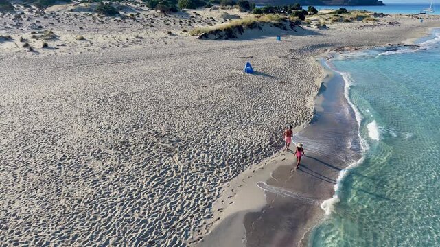 Wander along the pristine shores of Simos Beach in Elafonisos. Gentle waves lap the sandy coast while warm sunlight illuminates the tranquil setting, perfect for a relaxing getaway.