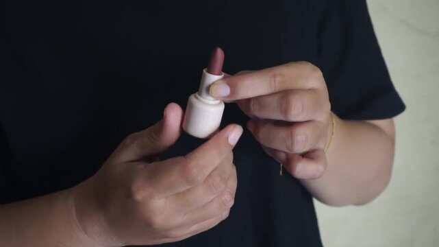 Close up of woman hands opening lipstick bottle cap preparing to apply makeup