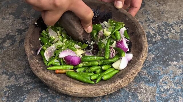 woman's hands grinding green chili and shallots