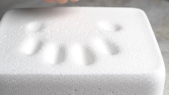 Woman's hand pressing down on white memory foam mattress or pillow, testing its soft and responsive texture