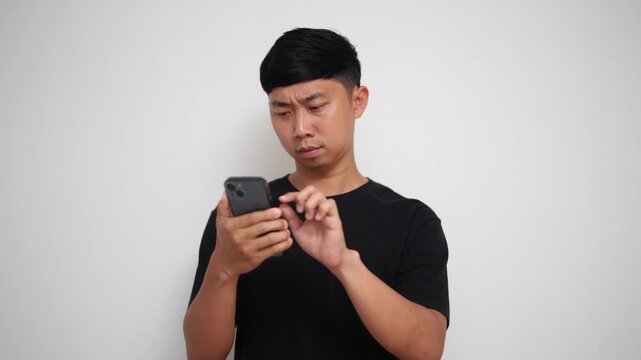 young Asian man looks confused and frustrated while using his mobile phone