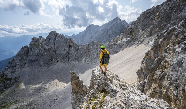Hiker on rocky outcrop, hiking trail to Lamsenspitze, behind cirque and rocky mountain peak with Mitterkarlspitze, Karwendel Mountains, Alpenpark Karwendel, Tyrol, Austria