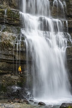 Adventure, Little hiker under large Cascata di Mezzo waterfall, long exposure, Vallesinella, Brenta, Trentino, Italy