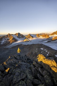 Mountaineers in front of a picturesque high mountain landscape at sunrise with alpenglow, glacier and rocky mountain peaks in the morning light, view at the Becher on mountain peak K&ouml;nigshofspitz and glacier &Uuml;beltalferner, Stubai Alps, South Tyrol, Italy