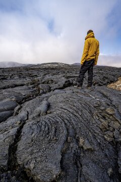 Tourist standing on petrified lava, volcanic stone in bizarre shapes, lava field, volcanic eruption, active table volcano Fagradalsfjall, Kr&yacute;suv&iacute;k volcanic system, Reykjanes Peninsula, Iceland