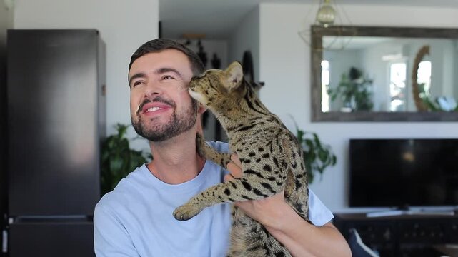 Cute video of a cat licking a man because he has cat food on his cheeks