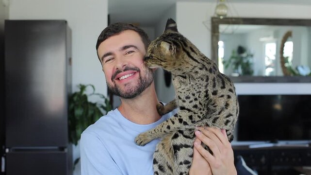 Cute video of a cat licking a man because he has cat food on his cheeks
