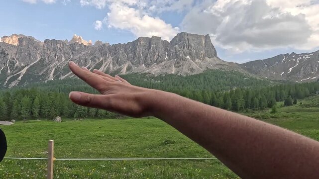 Intimate and emotive footage of a girl's hand trailing out of a car window while driving through the stunning mountain scenery of the Dolomites &mdash; a carefree and relatable road trip moment, northern It
