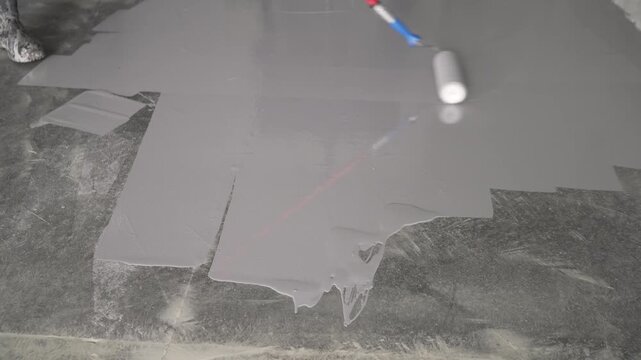 Freshly applied grey self leveling compound on concrete floor. Smooth grey self leveling compound spread across concrete floor surface. Construction material for flooring preparation. Even layer with 