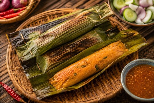 Traditional Otak-Otak with spiced fish paste wrapped in banana leaf, steamed or grilled for a flavorful Malaysian street food snack.