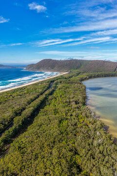 Aerial vertical scene capturing Seven Mile Beach and Wallis Lake near Forster, NSW, Australia, separated by a narrow strip of coastal land and leading towards Booti Hill. 