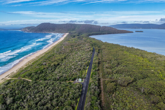 Aerial vertical scene capturing Seven Mile Beach and Wallis Lake near Forster, NSW, Australia, separated by a narrow strip of coastal land and leading towards Booti Hill. 