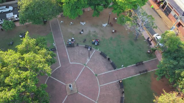 High-angle aerial drone shot starting with a top-down view of the circular design of Rub&eacute;n Dar&iacute;o Plaza, then rising and pulling back to reveal the surrounding residential urban landscape and cityscape