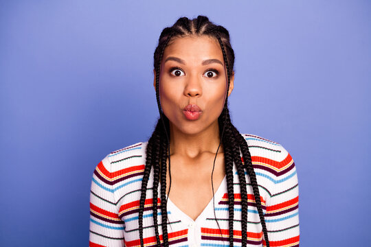 Young chic mixed race woman with braids making a playful kissy face against blue background stock photo