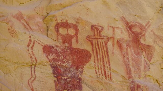 Pan of ancient red humanoid pictographs near Moab, Utah.