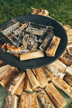 A barbecue for cooking outdoors in the summer. A fire with firewood stacked neatly around it.