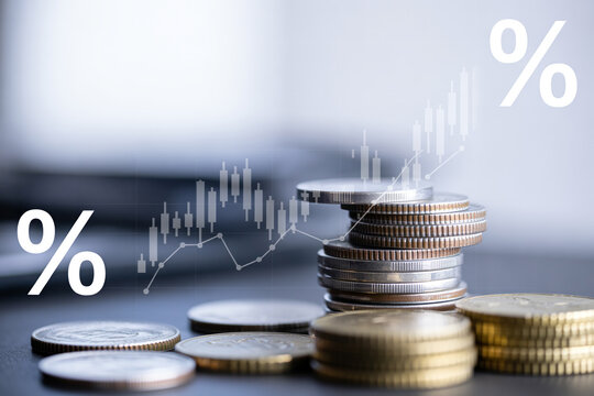Stack of coins with percent symbols and graph for financial growth on blur background.