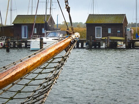 In the harbor of Gager on the island of R&uuml;gen, the wooden bowsprit of a sailing ship juts out towards the characteristic boathouses, which stand on wooden stilts in the water.