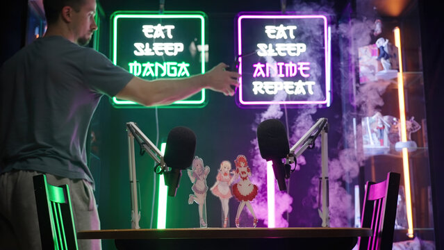 Person smoking the anime and manga podcast studio with neon signs and merch