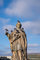 Obraz premium Stone statue covered with pigeons against a blue sky