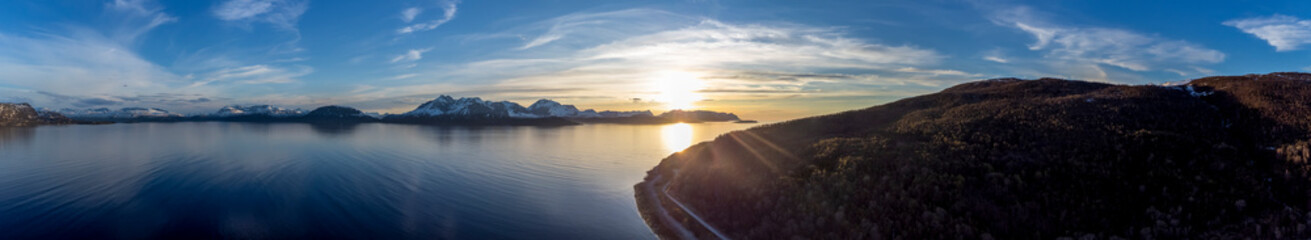 Fototapeta premium Panoramic drone shot overlooking the midnightsun on Fjord ( Reisafjorden ) and mountain Trolldalstinden in Storeng Kvaenangen, Troms, Norway