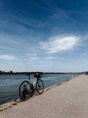 Fototapeta premium Gravel bicycle standing beside the Danube River on a sunny day. Cycling adventure, fitness and outdoor recreation concept.