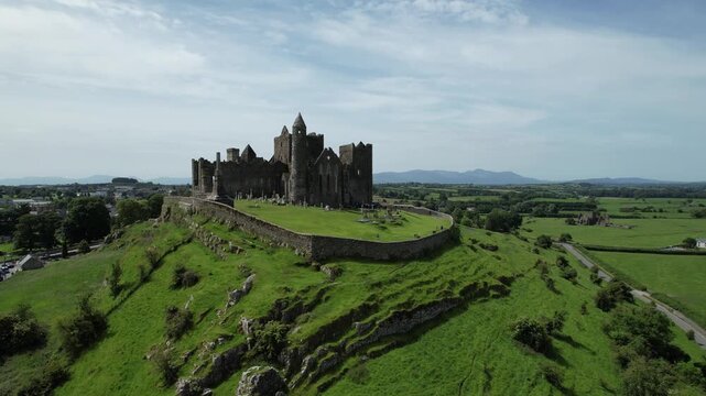 Aerial drone footage of the Rock of Cashel, a historic medieval fortress and cathedral complex in County Tipperary, Ireland, on a sunny day