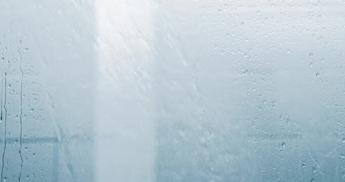 Water flowing behind a shower glass with droplets on the surface. Water Texture, Hygiene, cleanliness, daily water use, relaxation, and modern bathroom lifestyle