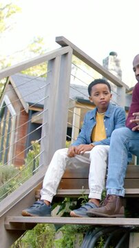 Vertical video: Listening boy folding hands on porch as adult speaking and gesturing, watch