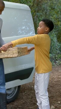 Vertical video: Offering man holding wicker lemon basket, boy in yellow shirt taking it at van rear