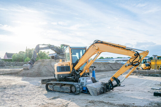 Heavy equipment for earthmoving and excavation works. excavator parked on a construction site with heavy machinery. Large excavator working on a pile of soil in the background under an overcast sky