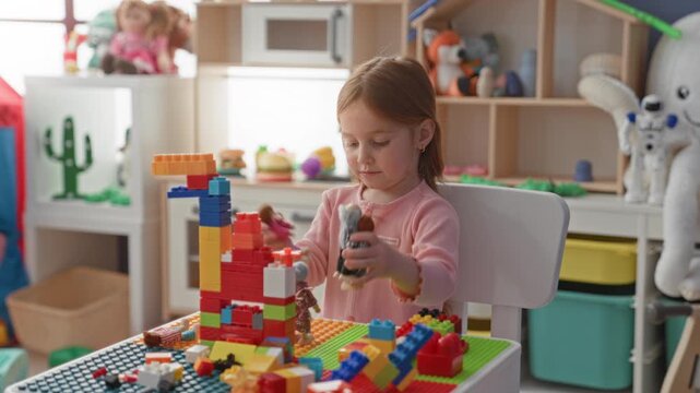 Girl stacking colorful blocks with bare hands on tabletop in playroom inside building; creative concentration.