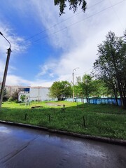 Naklejka premium Green residential courtyard playground after rain under blue sky