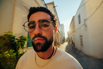 Young man in glasses and pearls walking city street © bernardbodo