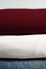 Fototapeta premium High-Resolution vertical close-up of stacked fabric layers with burgundy cotton white cloth and blue denim