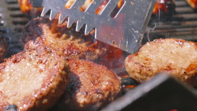 Summer BBQ with Juicy Beef Burger Being Moved on Flaming Grill with Open Flames Cooking Succulent Meat.